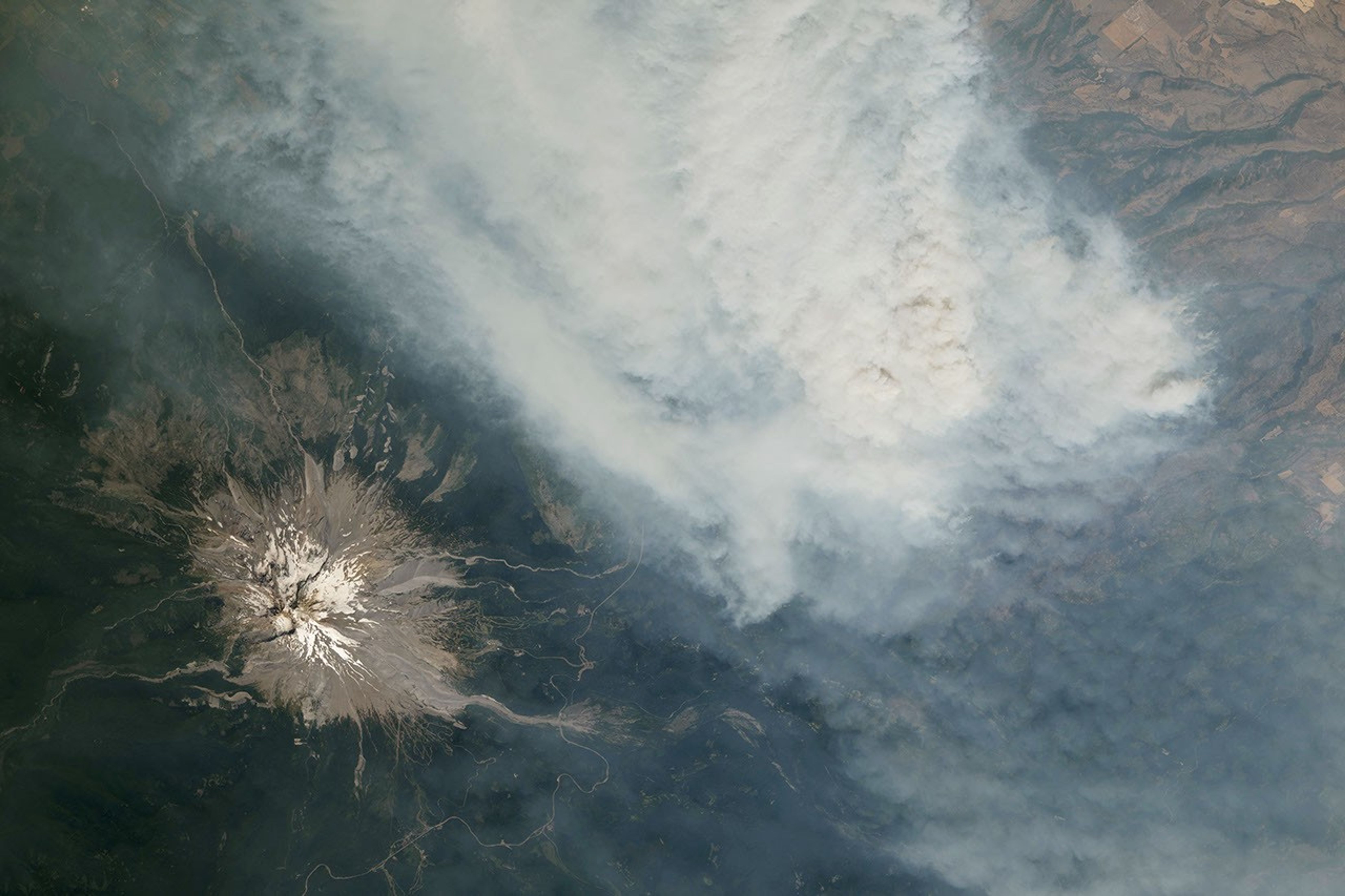 Mount Rainier surrounded by wildfire smoke as photographed from the International Space Station