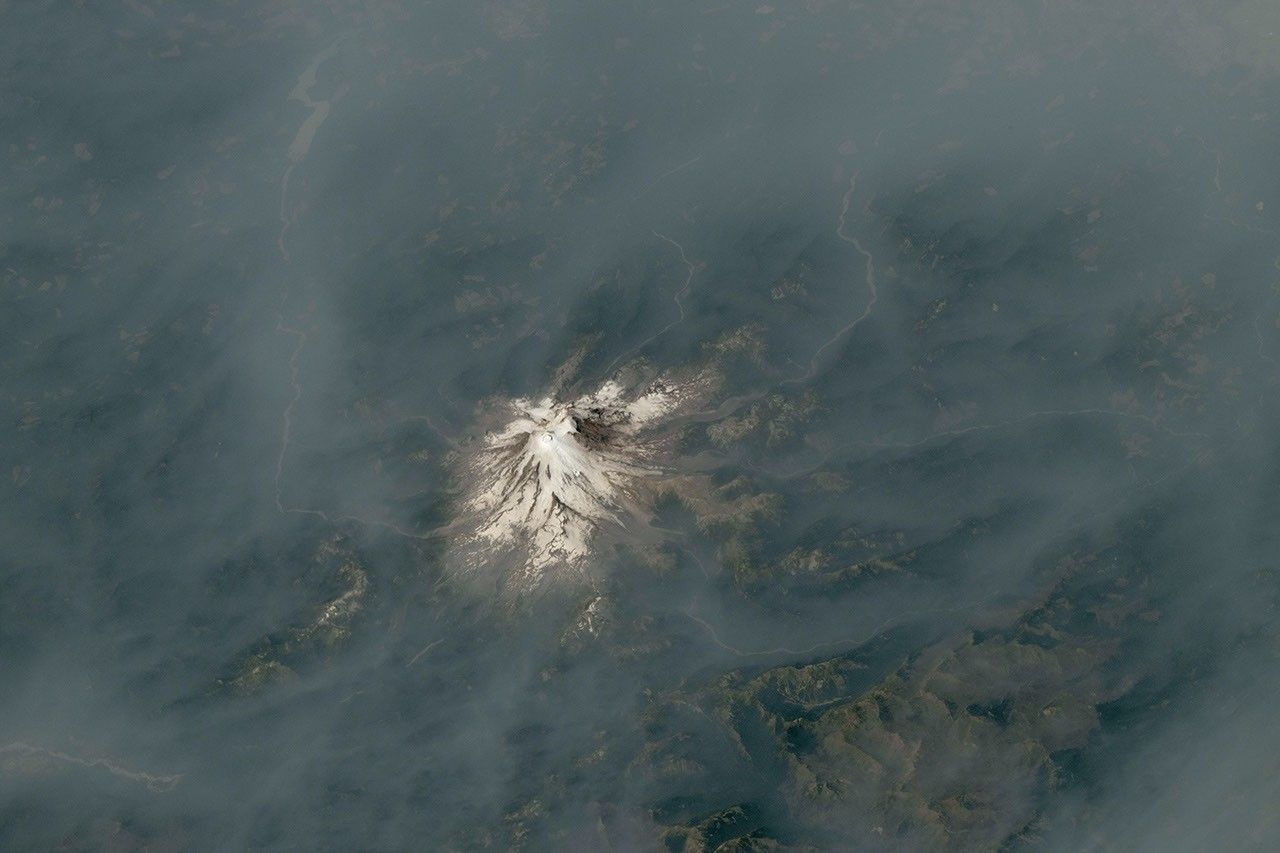 Wildfire smoke surrounds Mount Hood and the Cascade Range in an astronaut photograph from the International Space Station